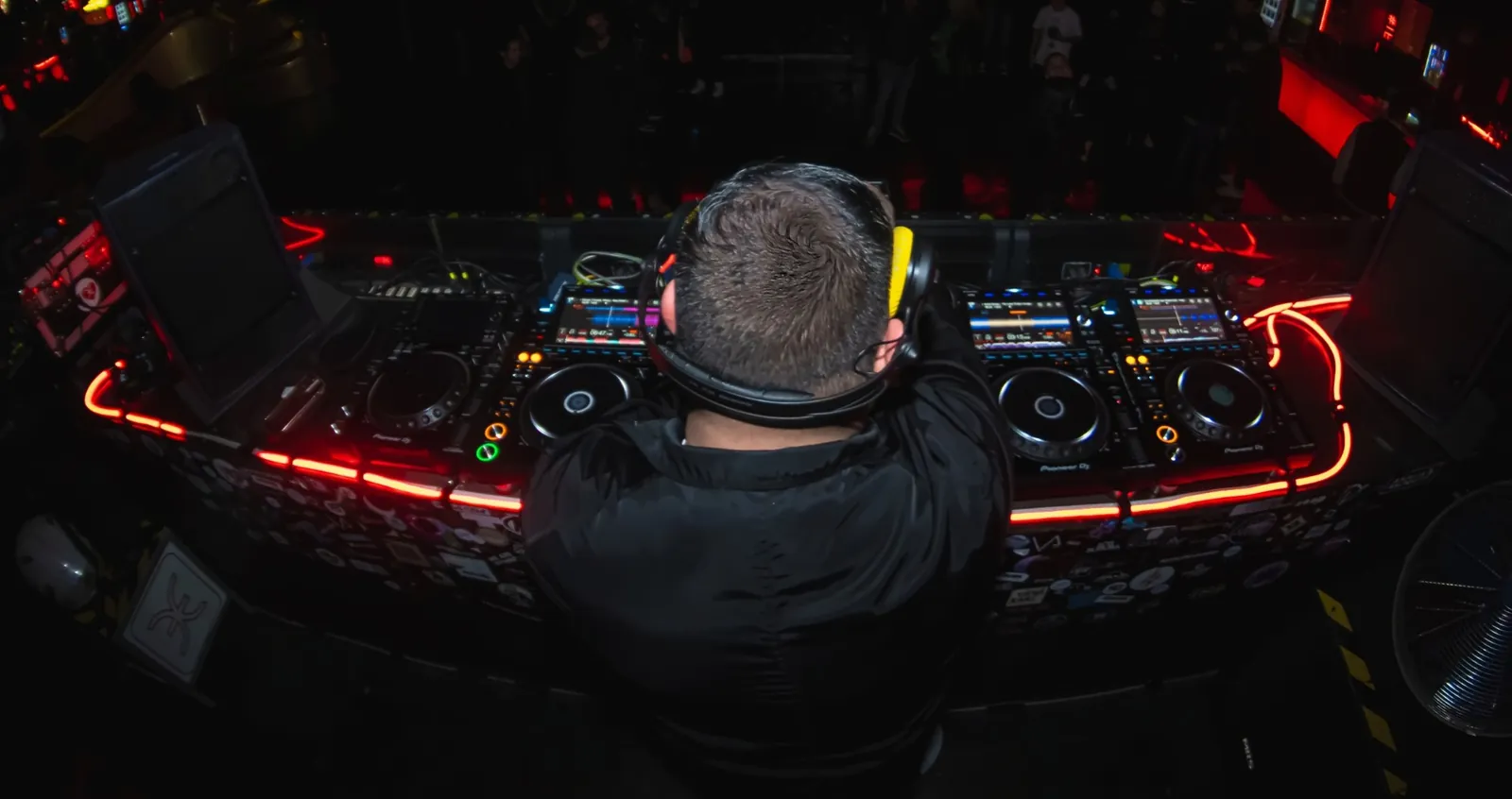 J ANTONY en cabina frente a los CDJ, con neón rojo